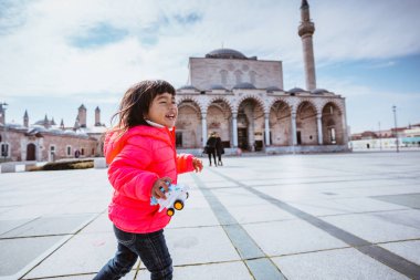 happy kid running around the square in city centre of konya turkey with mosque in the background