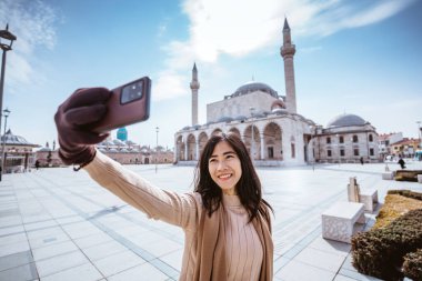 beautiful asian woman taking selfie portrait in front of the mosque in konya turkey