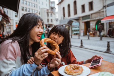mother and daughter enjoy playing while eating simit traditional bread of turkey in the morning