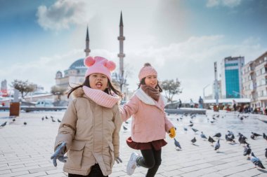 happy kids playing with pigeons in taksim square turkey during winter