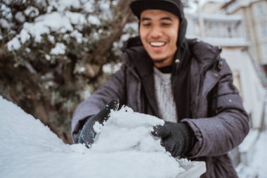 happy young man touching snow for the first time during visiting european country