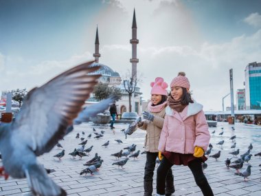 happy kids playing with pigeons in taksim square turkey during winter