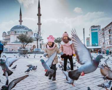 happy kids playing with pigeons in taksim square turkey during winter