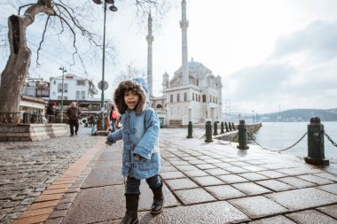 happy kid running around the square in city centre of konya turkey with mosque in the background