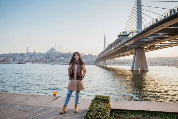 young girl relaxing on the side of bosphorus during sunset. beautiful woman with istanbul city scape at the background