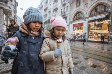 portrait of kid enjoy having ice cream while walking in snow fall