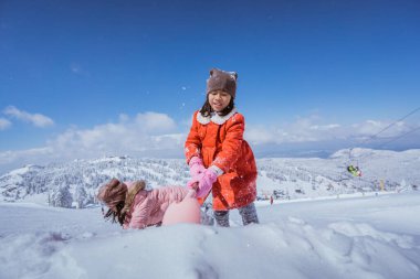 two girl playing with snow. asian little sister enjoy their time in snowy winter together