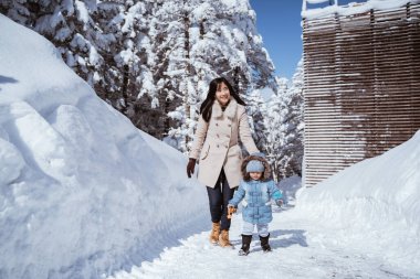 portrait of a mother walking with her kid in snowy mountain