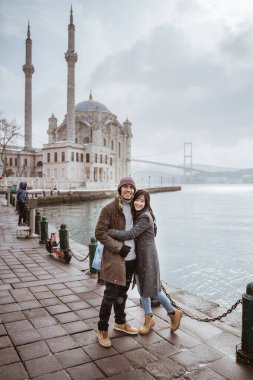 beautiful couple portrait smiling while visiting ortakoy mosque in turkey istanbul
