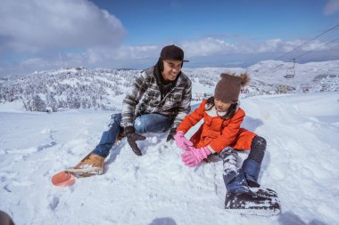 happy father and daughter playing with snow in the mountain peak