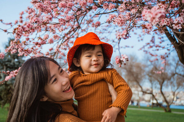 beautiful mother and daughter enjoy in the park during cherry blossom festival