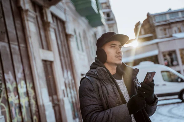 portrait of a man wearing jacket and holding his phone with sunset at the background