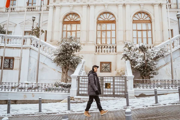 asian man walking in historical old town in istanbul during snow winter season