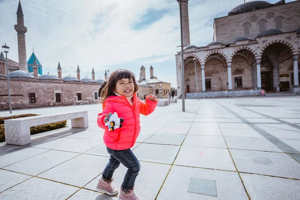 happy kid running around the square in city centre of konya turkey with mosque in the background