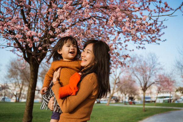beautiful mother and daughter enjoy in the park during cherry blossom festival