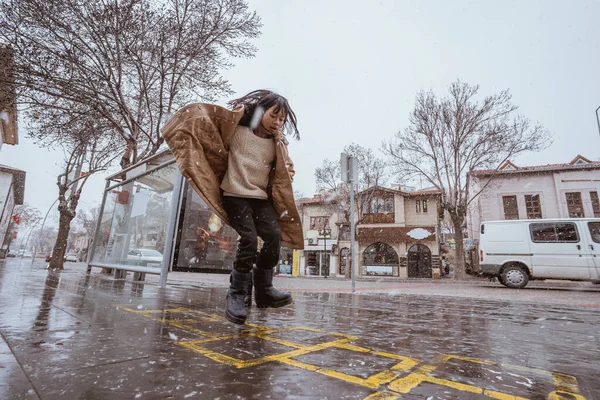 girl playing hopscotch on sidewalk during winter and snow fall