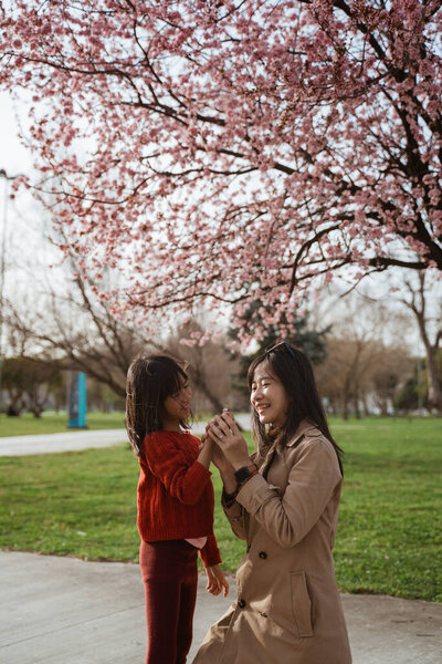 beautiful mother and daughter enjoy in the park during cherry blossom festival