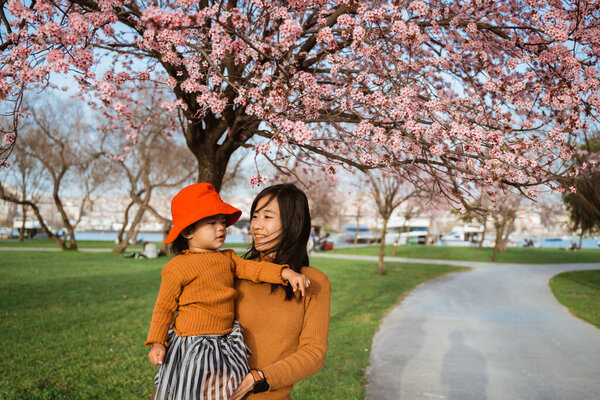 beautiful mother and daughter enjoy in the park during cherry blossom festival