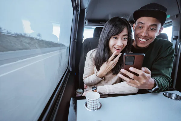 Suprised Couple Using Smartphone Together While Traveling Car Sitting Window — Stockfoto