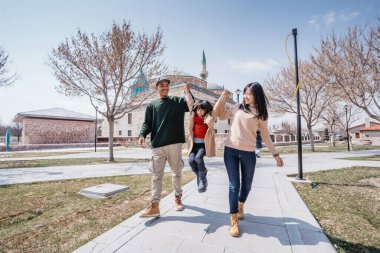 parent walking and playing with daughter while visiting turkey on holiday vacation with mosque at the background