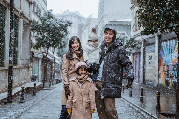 portrait of asian family wearing warm clothing standing in the middle of snow fall in winter. family travel in turkey