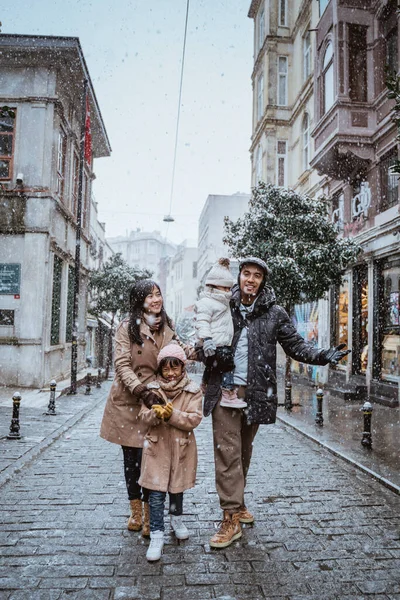 happy asian family traveling in beautiful city during snow fall winter in turkey