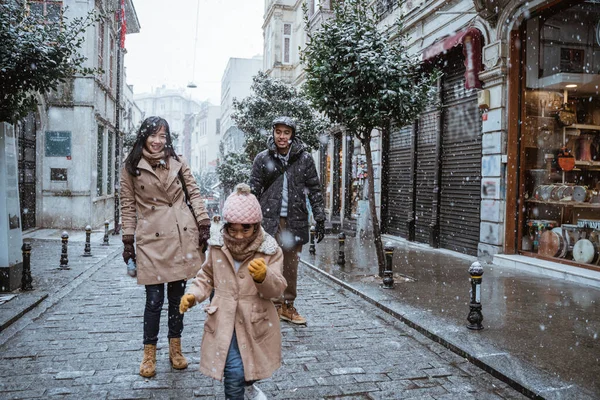 happy asian family traveling in beautiful city during snow fall winter in turkey