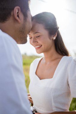 man kissing girlfriend on forehead in the street in the countryside. Romantic young man giving a kiss to his woman in the city street. Loving young couple