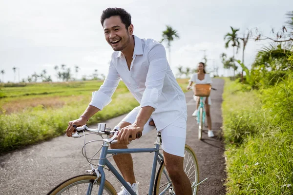Happy Young Man Riding Bicycle While Her Girlfriend Background — Fotografia de Stock