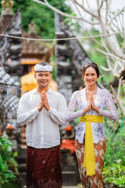 happy beautiful balinese couple greeting and smiling gesture at camera