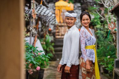 portrait of beautiful woman in balinese kebaya with her husband in typical bali village