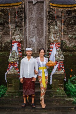 beautiful balinese couple going to pura in the morning to do the prayer and make offering to the god in holy galungan day