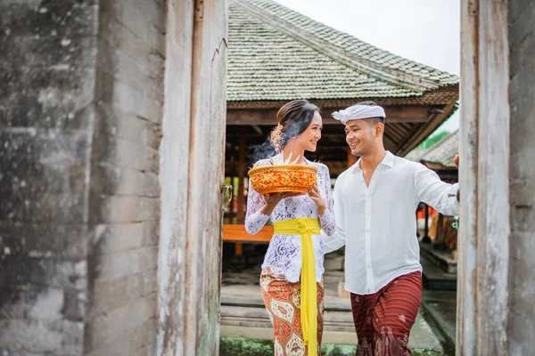beautiful balinese couple going to pura in the morning to do the prayer and make offering to the god in holy galungan day