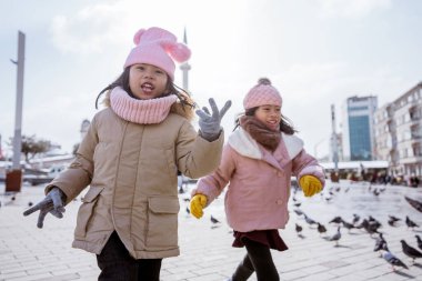 two little girl playing chasing a bird in istanbul taksim city square