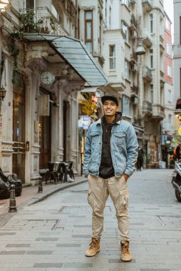 man with denim jacket smiling to camera full body portrait at the alley old town