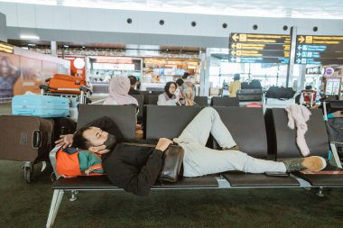tired young man laying on a bench at the airport terminal