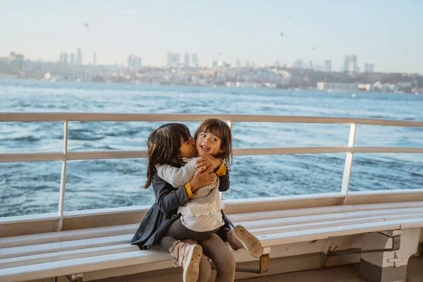 happy little girl sitting with her sister on a ferryboat on their way crossing the bosphorus