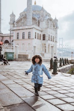 happy kid running around the square in turkey with ortakoy mosque in the background