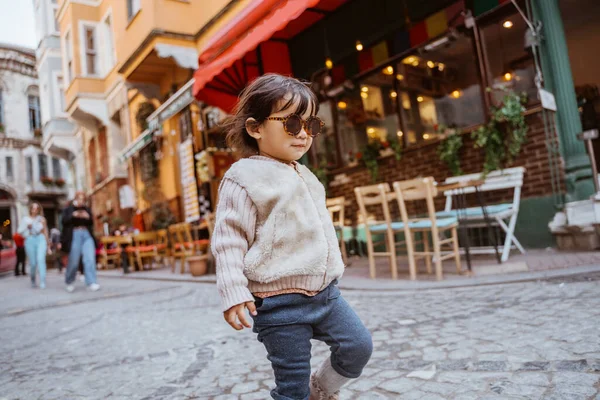cute stylish kid walking around the old town area wearing sunglasses