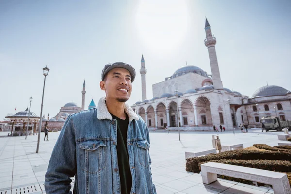 muslim young man standing in front of the mosque and mevlana museum in konya turkey