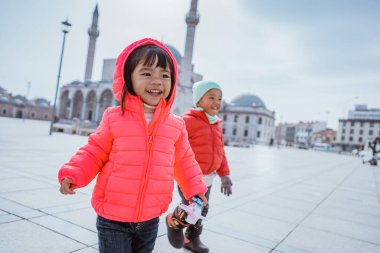 happy kid running around the square in city centre of konya turkey with mosque in the background