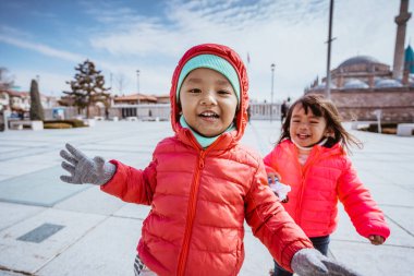 happy kid running around the square in city centre of konya turkey with mosque in the background