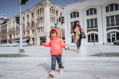 happy kid running around the square in city centre with mother