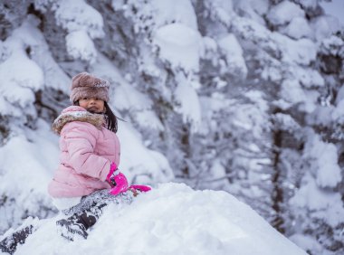 happy little girl playing outside in the snow with clear sky