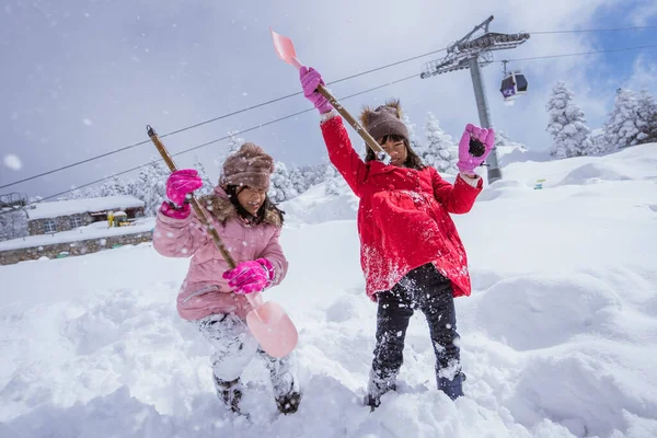 two girl playing with snow. asian little sister enjoy their time in snowy winter together