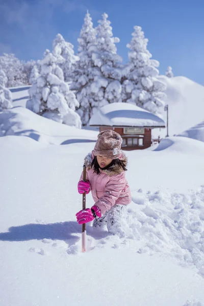 happy little girl playing outside in the snow with clear sky