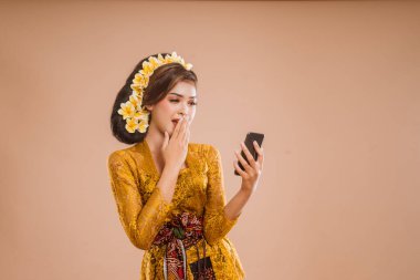 shocked balinese woman while looking at her mobile phone device