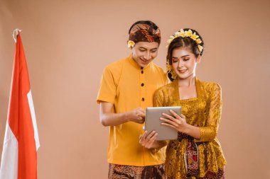 happy balinese couple using tablet pc together over isolated background