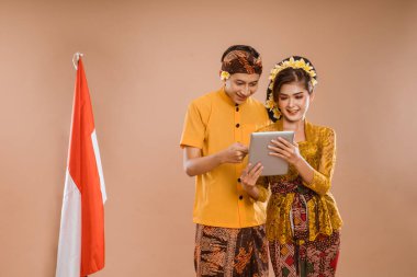 happy balinese couple using tablet pc together over isolated background