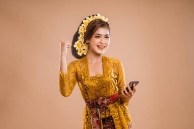 excited woman with balinese traditional kebaya costume over isolated background